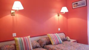 a bedroom with red walls and a couch and two lamps at Maison Hôtel Aux Cerisiers in La Forêt-Fouesnant