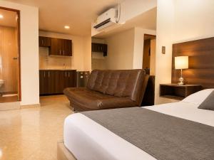 a hotel room with a bed and a leather chair at Hotel Laureles Palo Alto in Medellín