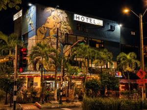 a hotel with a mural on the side of it at night at Hotel Laureles Palo Alto in Medellín