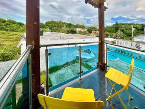a balcony with yellow chairs and a swimming pool at Villa Fidelina Picsina in Río San Juan