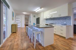 a large kitchen with white cabinets and bar stools at Billfish in Exmouth