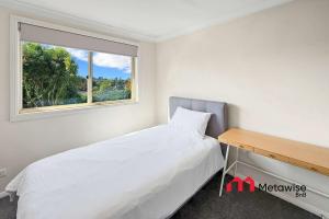 a small bedroom with a bed and a window at Spacious 4-Bedroom Home in Cherrybrook in Cherrybrook