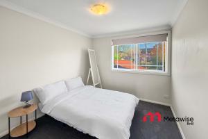 a bedroom with a white bed and a window at Spacious 4-Bedroom Home in Cherrybrook in Cherrybrook