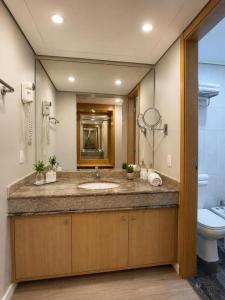 a bathroom with a sink and a toilet and a mirror at Sol Alphaville Hotel By Your Alpha Stay 1602 in Barueri +6 photos