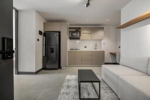 a living room with a white couch and a refrigerator at Apartamentos HOUSY Laureles in Medellín