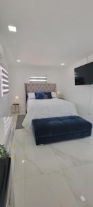 a white bedroom with a large bed with blue pillows at Hard Rock Area Modern Studio in Miami Gardens