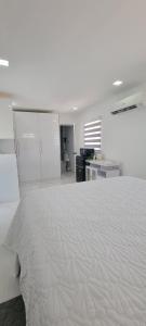 a white bedroom with a large bed and a desk at Hard Rock Area Modern Studio in Miami Gardens
