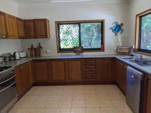 a kitchen with wooden cabinets and a sink and a window at Daintree Private Escape in Cow Bay