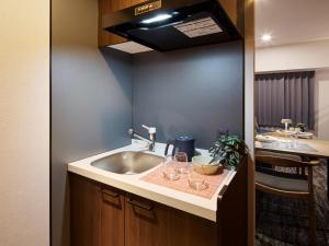a kitchen with a sink and wine glasses on a counter at Minn Hakata Station East in Sumiyoshi