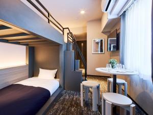 a room with a bed and a table and two stools at Minn Hakata Station East in Sumiyoshi