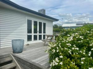a wooden deck with a picnic table and some flowers at Dublin No 5 in Martinborough