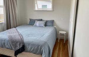 a bedroom with a bed with blue sheets and a window at Dublin No 5 in Martinborough