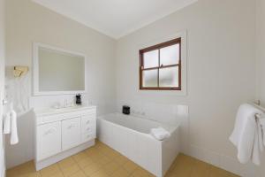 a white bathroom with a bath tub and a window at Audrey Wilkinson Vineyard in Pokolbin