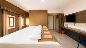 a bedroom with a large bed with pillows on it at Ventions Sharia Hotel in Jomblang +37 photos