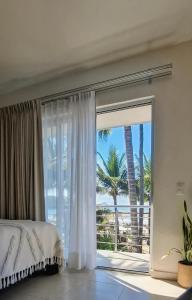 a bedroom with a large window with a view of the ocean at Hotel Majo Sayulita in Sayulita