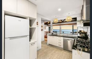 a kitchen with white cabinets and a view of the ocean at Gate Access to the Beach in Edithvale