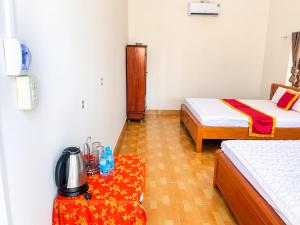 a room with two beds and a table with a tea kettle at Khách sạn Thu Hòn Rơm Phan Thiết in Phan Thiet