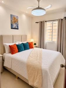 a bedroom with a large white bed with colorful pillows at Oceanfront AC Wi-Fi Coffee Summer vacation in La Cana
