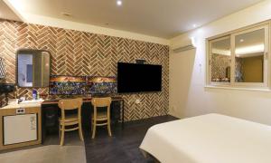 a room with a bed and a desk with a television at Hotel H2 in Ulsan +8 photos