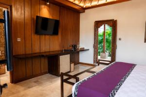 a bedroom with a bed and a tv on a wall at Mumbul Ubud in Ubud
