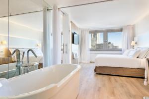 a bathroom with a tub and a bed in a room at Meliá Madrid Princesa in Madrid