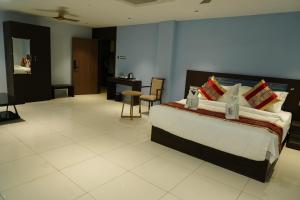 a bedroom with a bed and a table and chairs at MRM Grand Park in Pudukkottai +2 photos