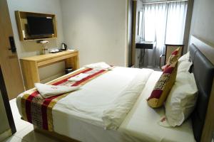 a bed in a hotel room with a television at MRM Grand Park in Pudukkottai