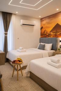 two beds in a hotel room with a bowl of fruit on a table at Golden RZ pyramids view in Cairo