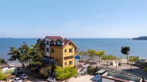 a yellow house on the beach next to the water at Yeongheungdo Rainbow Ocean View Pension in Incheon