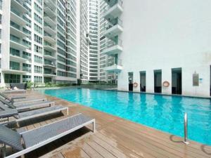 a large swimming pool with chairs and buildings at Empire Hostel Regalia in Kuala Lumpur