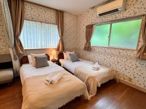 two beds in a room with two windows at 伊豆ビーチクラブ in Shimoda