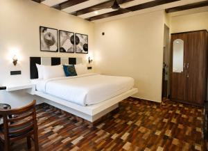 a bedroom with a white bed and a wooden floor at Coco Nest Mandrem in Mandrem +9 photos