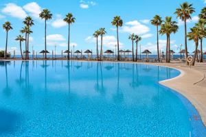 a swimming pool with palm trees and the ocean at Holiday World Polynesia, Affiliated by Meliá in Benalmádena