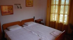 a bedroom with a bed with white sheets and a window at Panormos Palace in Panormos Skopelos