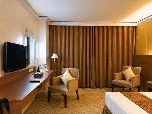 a hotel room with a desk with two chairs and a television at The Royal Mandaya Hotel in Davao City