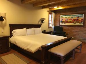 1 dormitorio con 1 cama grande y 1 silla en Puertolago Country Inn & Resort, en Otavalo