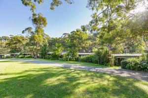 an open yard with trees and a house at Sandpiper On Smiths Lake in Smiths Lake
