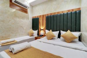 a bedroom with two beds and a green headboard at Hotel Omega in Mumbai