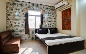 a bedroom with a bed and a couch and a window at Hotel soni plaza in Jhālrapātan