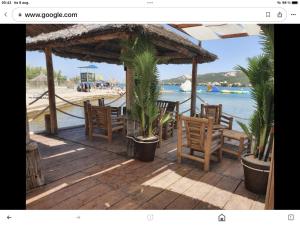 a deck with chairs and palm trees on a beach at Apartments Gumla 1 in Stara Novalja
