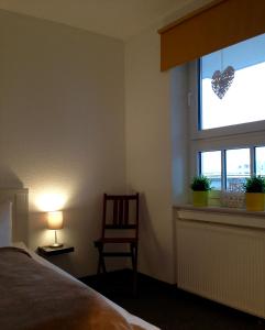 Schlafzimmer mit einem Bett und einem Fenster mit einem Stuhl in der Unterkunft de Rob Plat in Dorum Neufeld