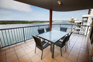 a table and chairs on a balcony with a view of the water at On The River Apartments in Maroochydore