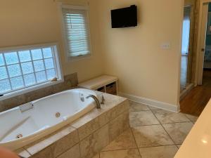 a large bathroom with a tub and a television at Tortuga home in Holden Beach