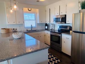 a kitchen with white cabinets and stainless steel appliances at Dune Deck North - Duplex in Holden Beach