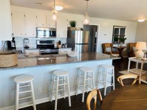 a kitchen with a counter and bar stools at Dune Deck North - Duplex in Holden Beach