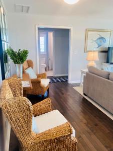 a living room with wicker chairs and a table at Dune Deck North - Duplex in Holden Beach