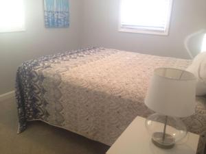 a bedroom with a bed with a lamp and a table at Dune Deck South - Duplex in Holden Beach