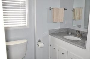 a white bathroom with a toilet and a sink at Dune Deck South - Duplex in Holden Beach