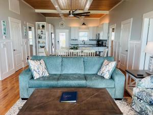 a living room with a blue couch and a kitchen at Holden R Breath in Holden Beach