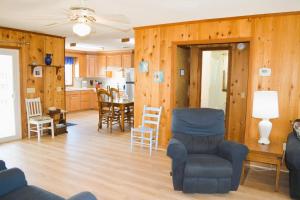 a living room with wooden walls and a table and chairs at Do-Little Dock in Holden Beach